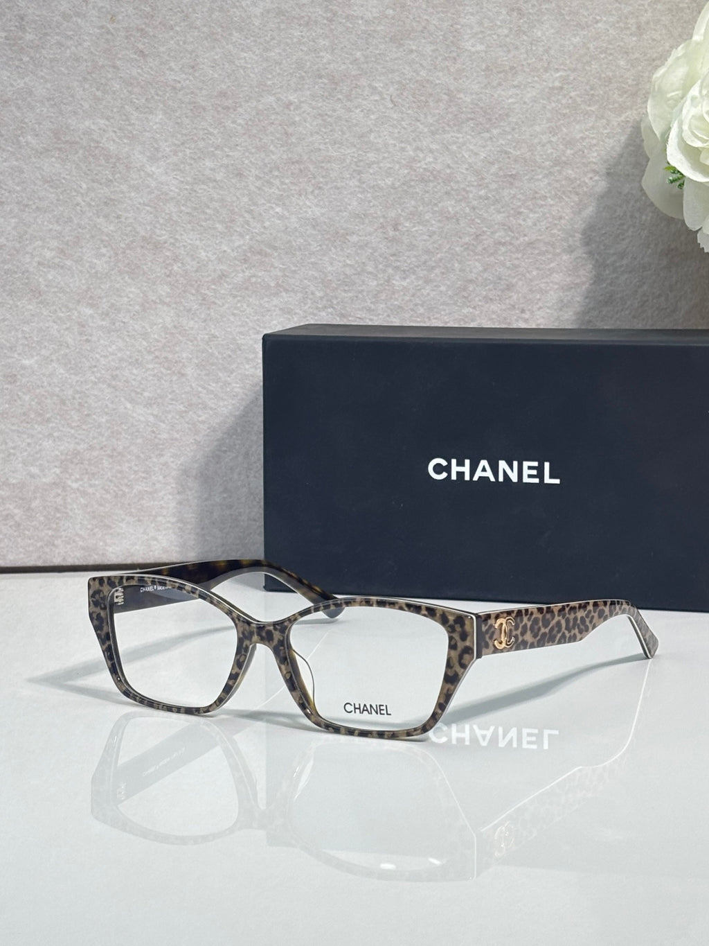 Chanel eyeglasses with dark frames and leopard-print temples, clear lenses