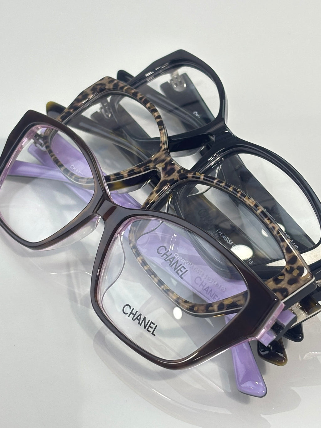 Chanel eyeglasses with dark frames, leopard-print temples, purple-tinted lenses