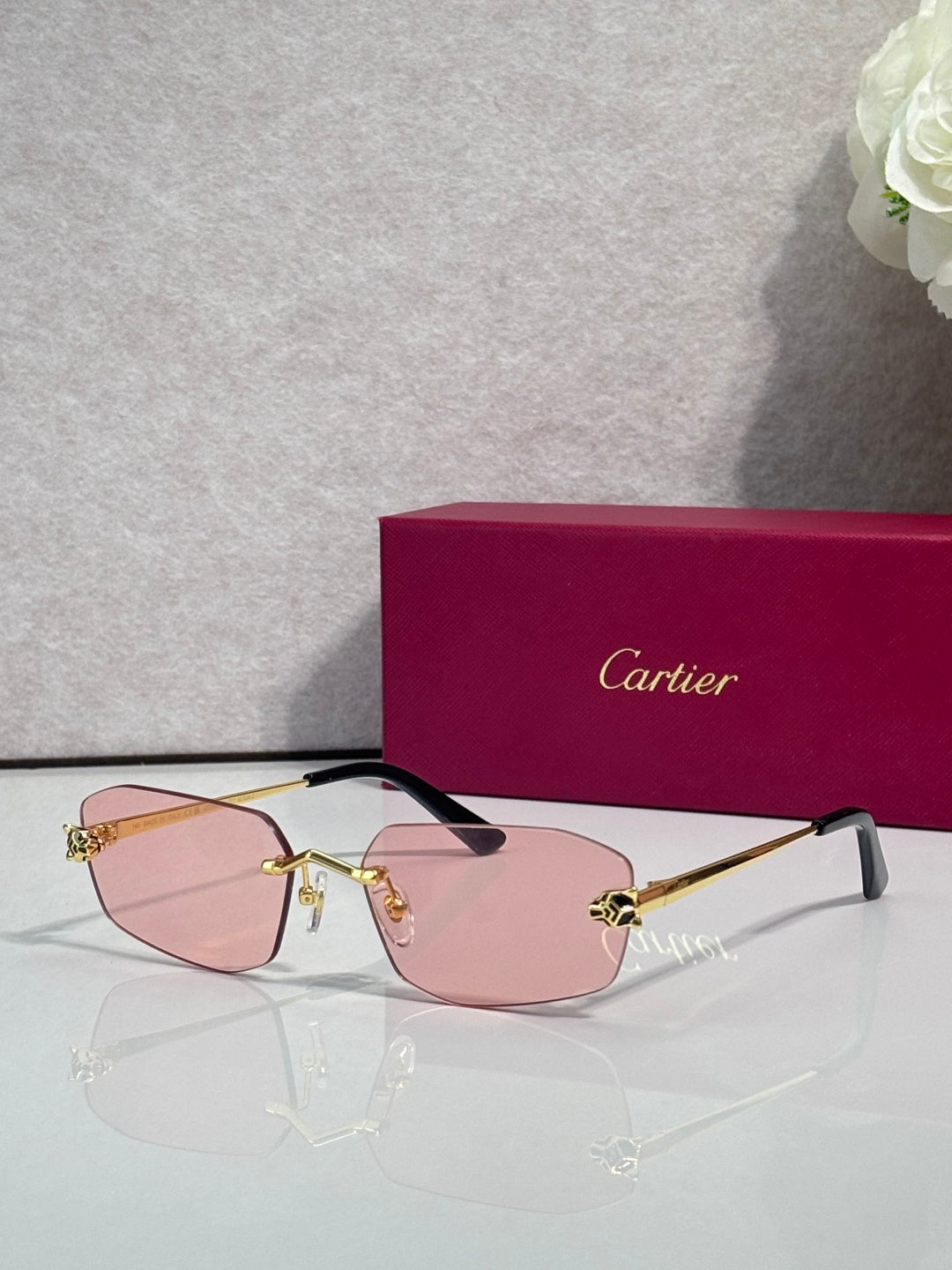 Cartier sunglasses with gold frame, rose-pink lenses, black temple tips