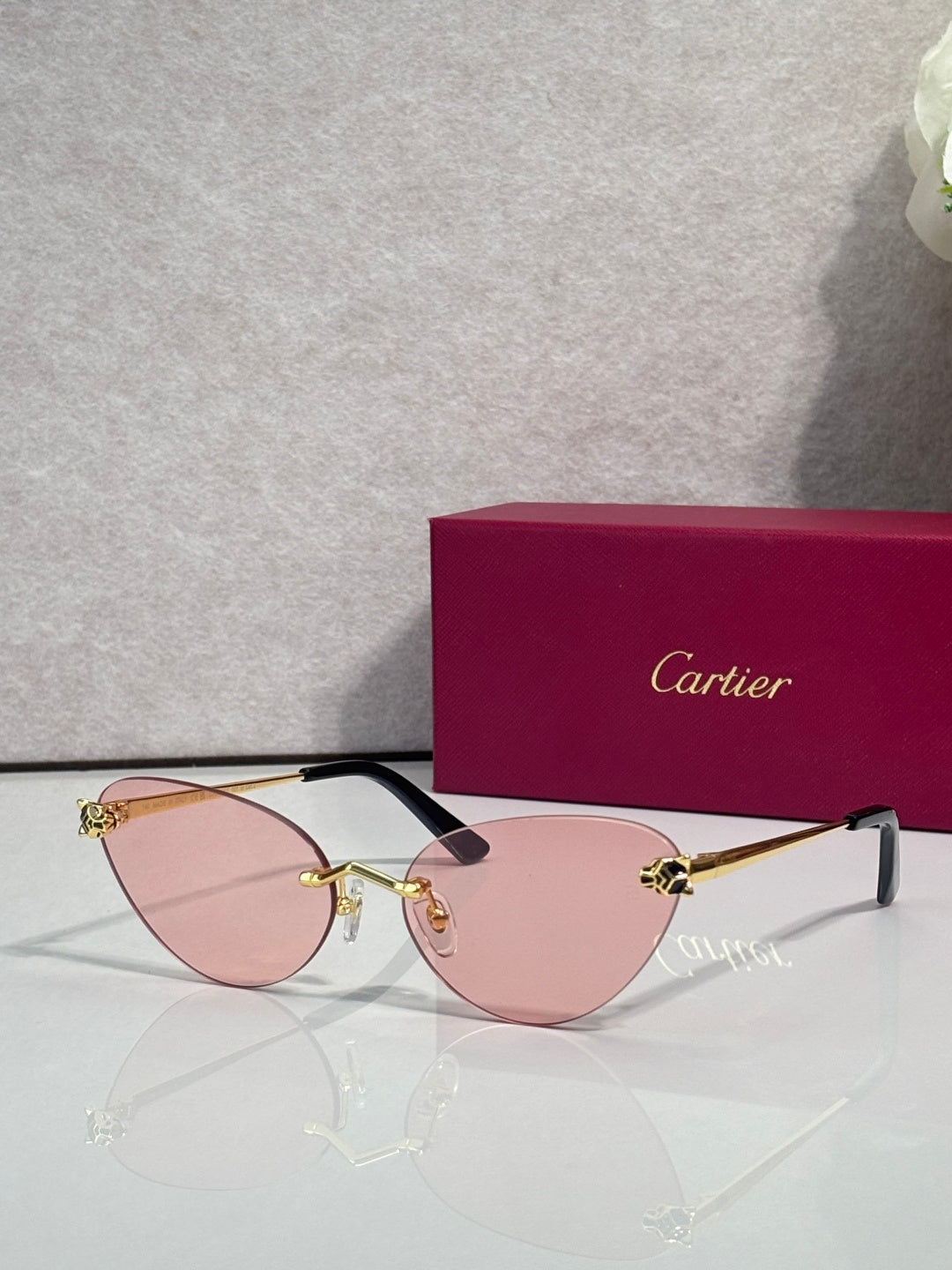 Cartier glasses with gold frame, pink lenses, and black temples