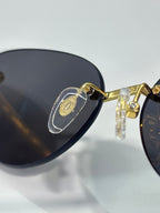 Cartier glasses close-up: gold frame with dark lenses and decorative hinge