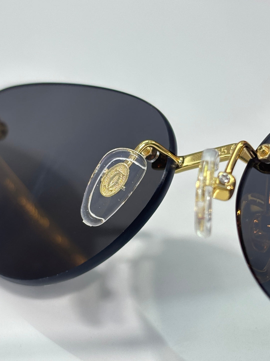Cartier glasses close-up: gold frame with dark lenses and decorative hinge