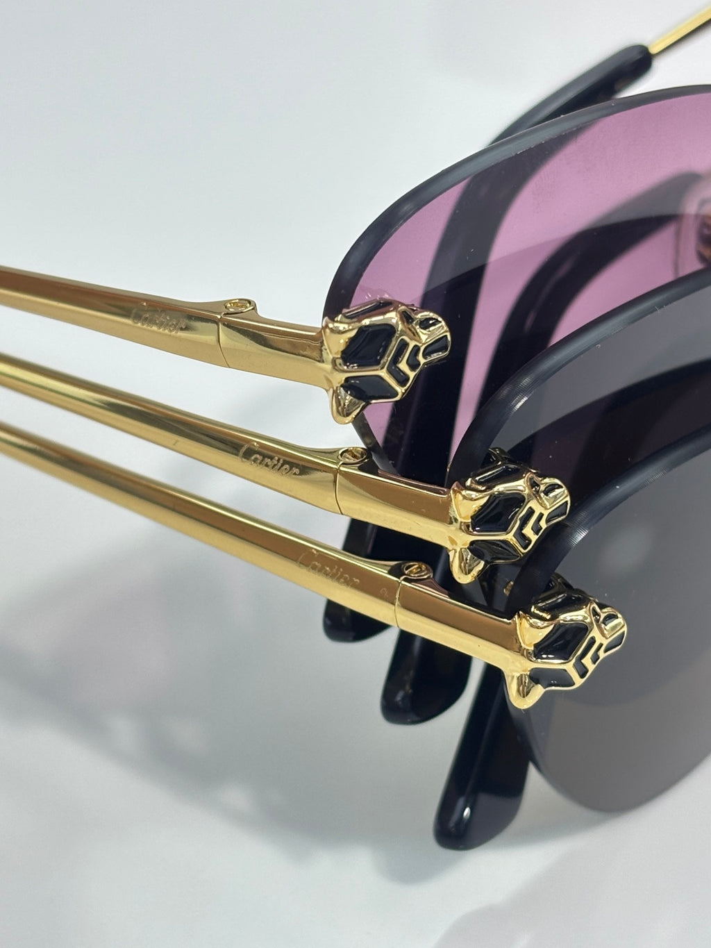 Cartier glasses close-up: gold frame with pink-tinted lenses and geometric studs