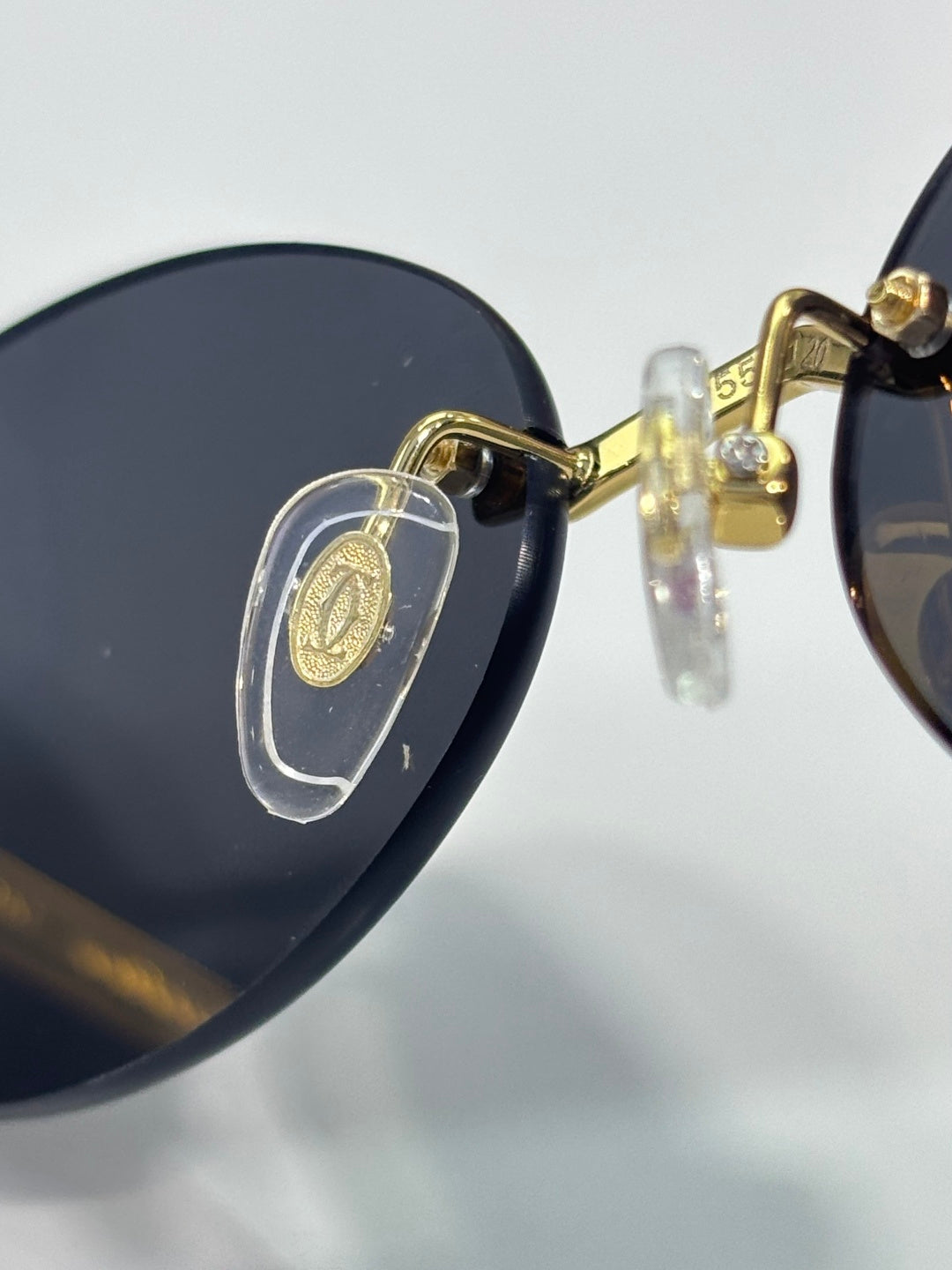 Cartier round sunglasses close-up: gold detail on dark lens and temple