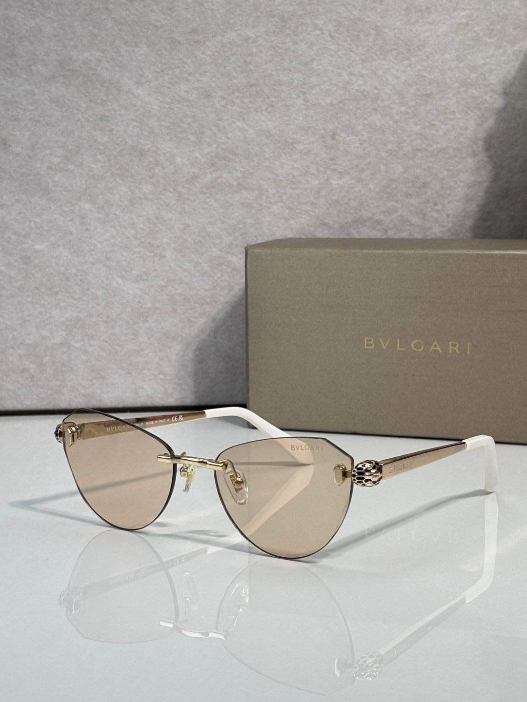 Sunglasses with light tan tinted lenses, thin gold frame, and black temple tips
