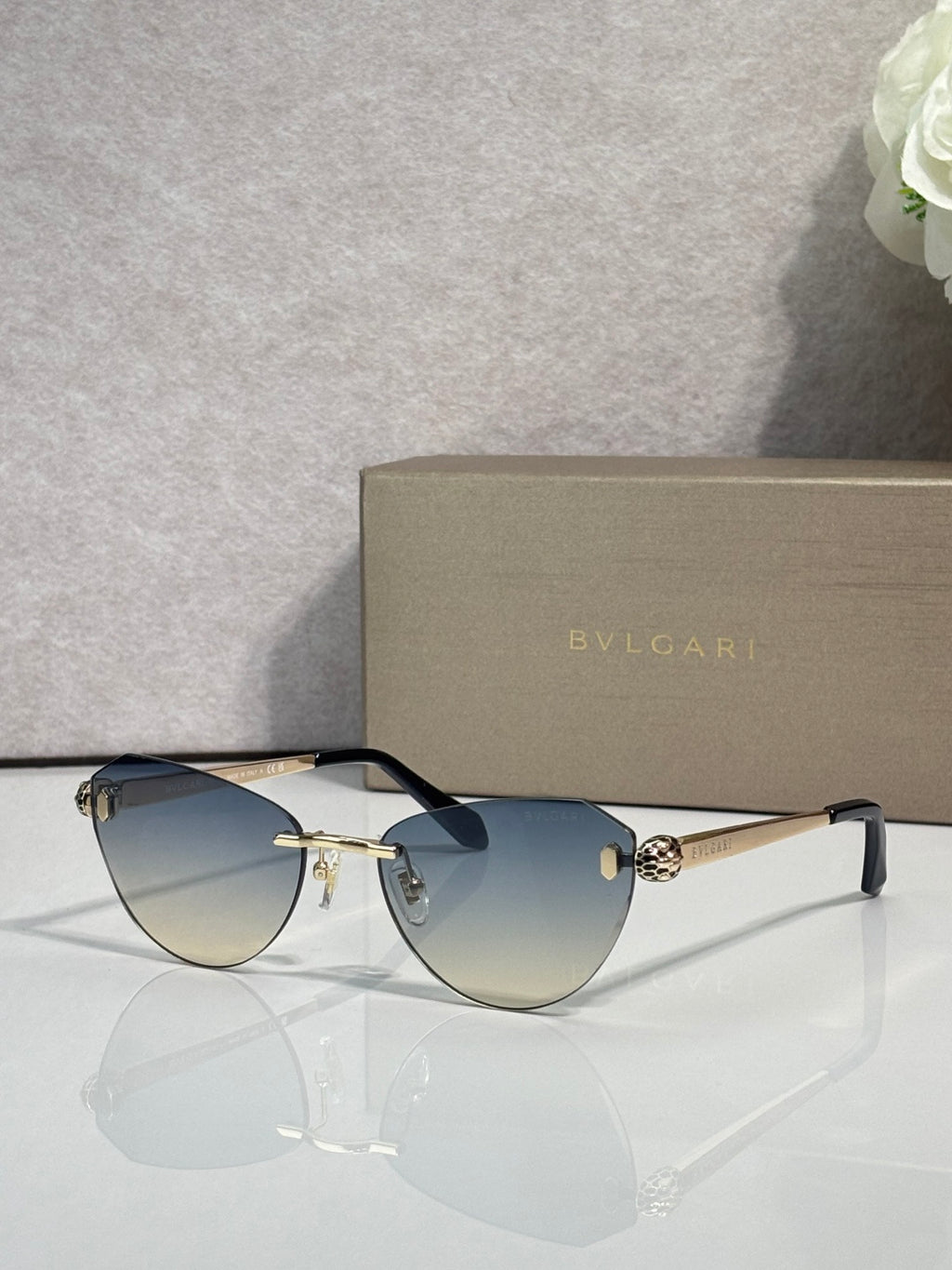 Sunglasses with blue gradient lenses, black frame, and gold metal accents