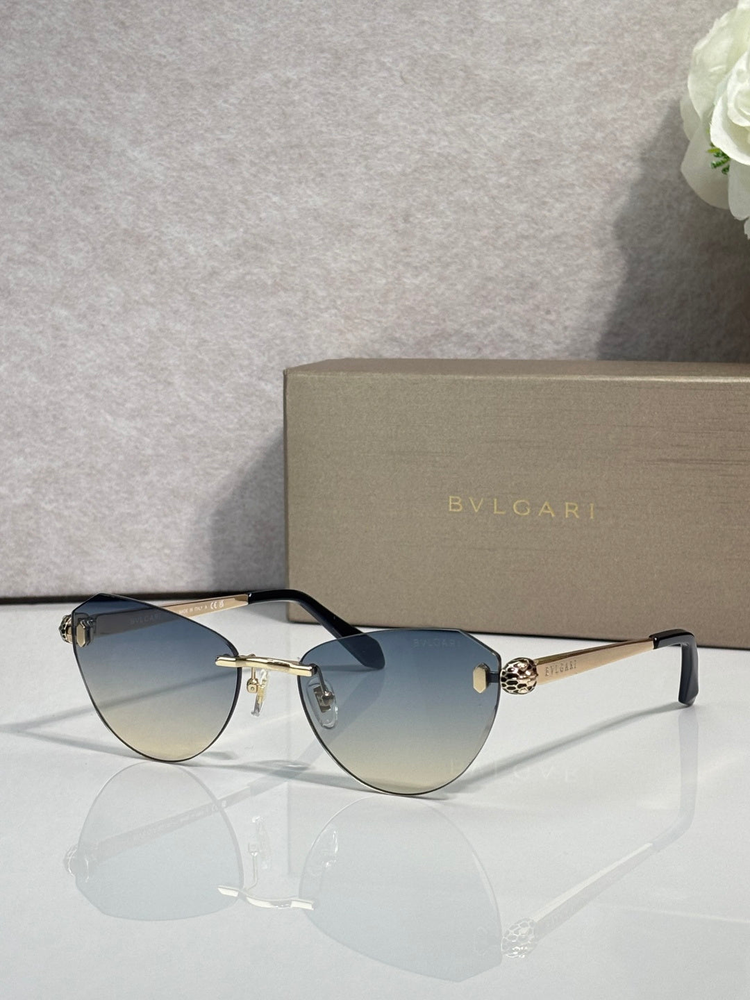 Sunglasses with blue gradient lenses, black frame, and gold metal accents