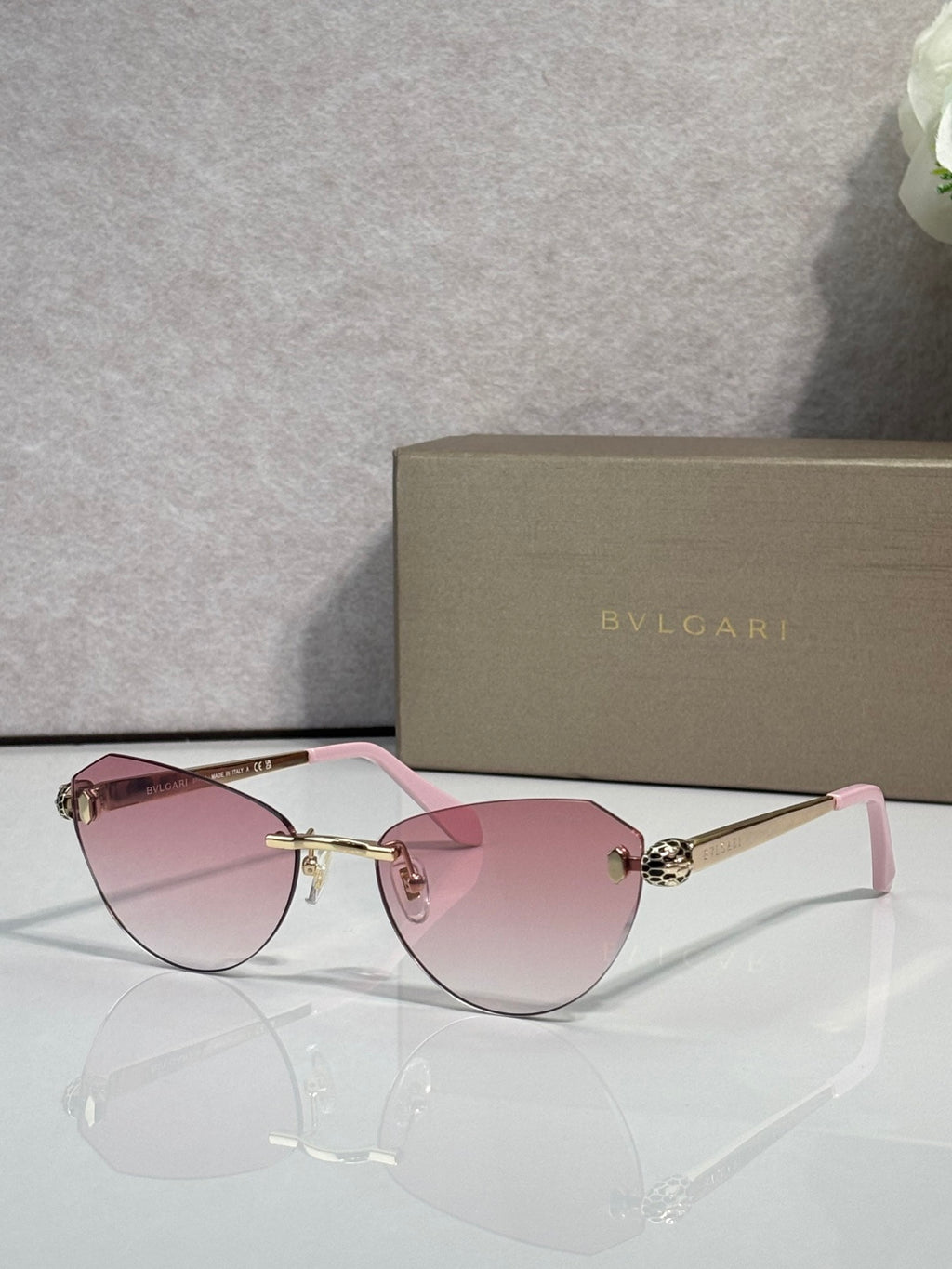 Sunglasses with pink tinted lenses, black frame, and gold metal bridge