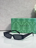 Gucci sunglasses with black frames, green arms, and dark tinted lenses