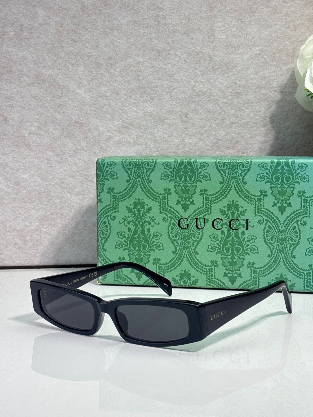 Gucci sunglasses with black frames, green arms, and dark tinted lenses