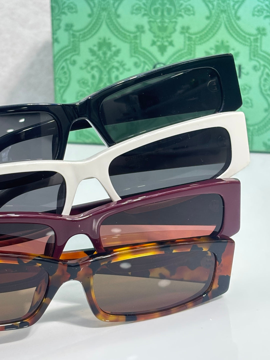 Gucci sunglasses layered with white frames and burgundy arms