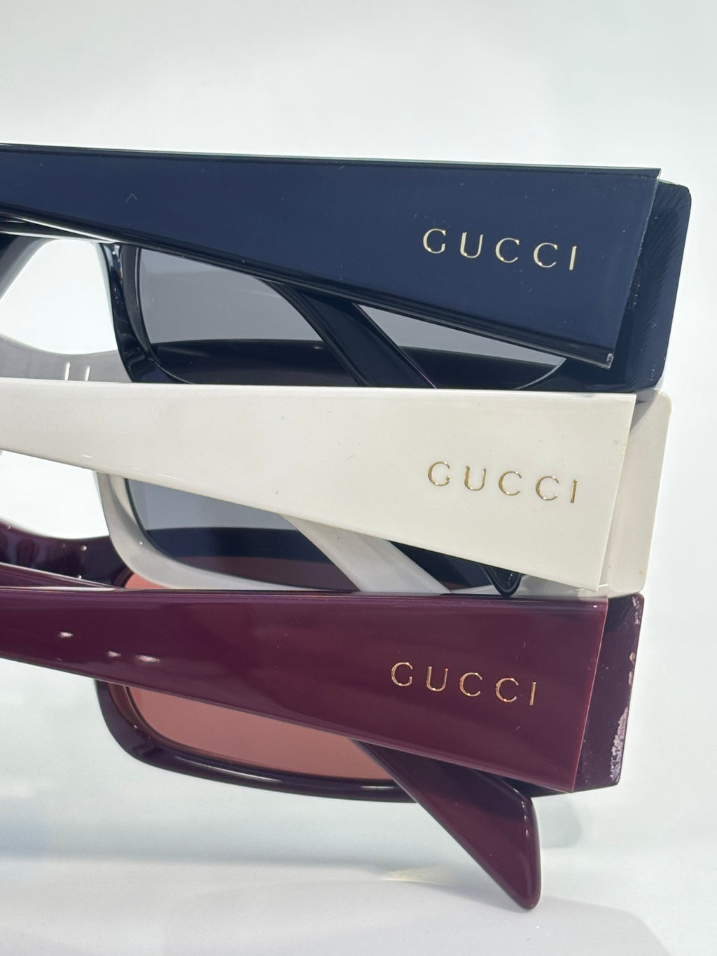 Gucci sunglasses with white frames, navy temples, and dark tinted lenses