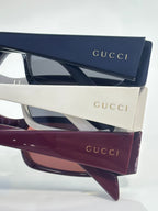 Gucci sunglasses with white frames, navy temples, and dark tinted lenses