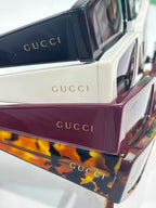 Gucci sunglasses stack showing white, maroon, and tortoise frames with dark lenses
