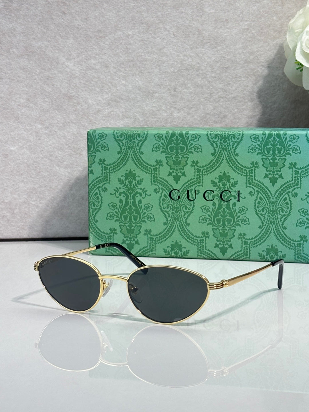Gucci sunglasses with gold-tone frame and dark oval lenses