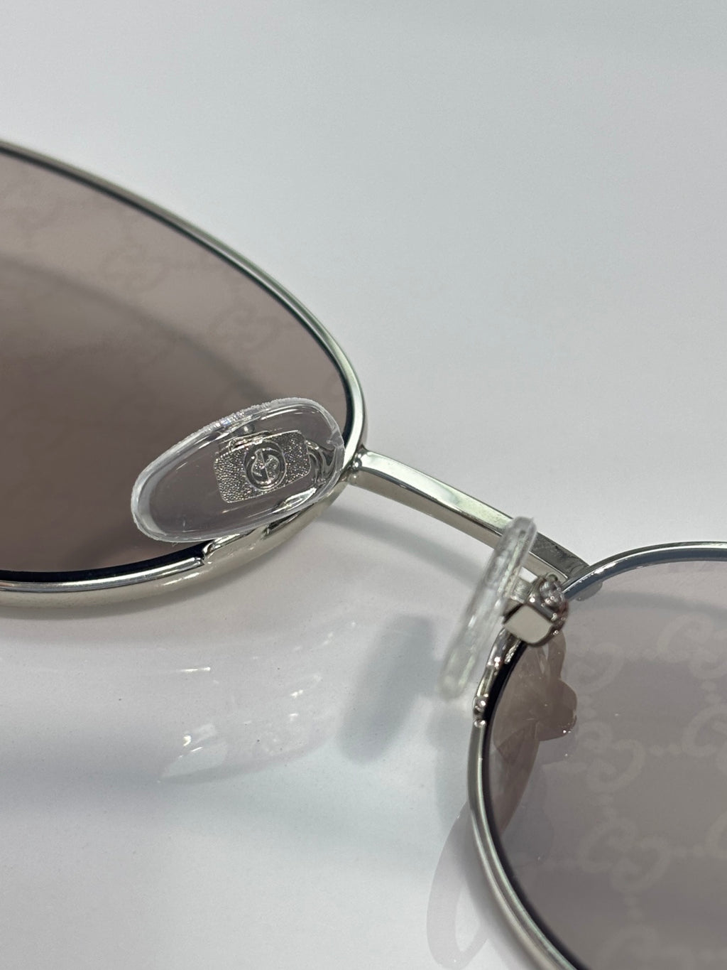 Gucci sunglasses close-up: silver bridge and temple with logo detail