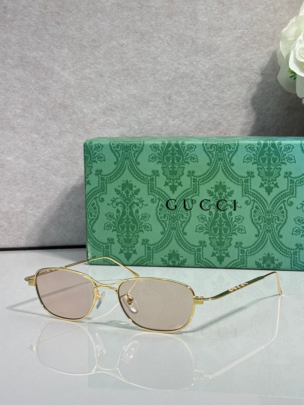 Gucci sunglasses with gold frame and light tinted lenses, oval shape