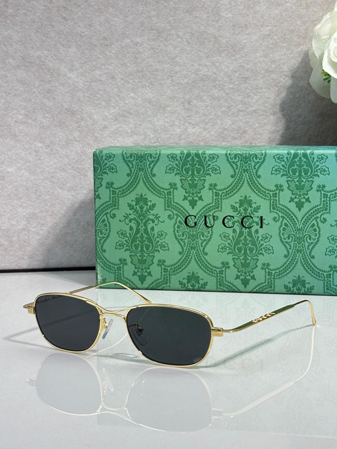 Gucci sunglasses with gold frame and dark lenses, oval shape