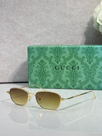 Gucci sunglasses with gold frame and olive tinted lenses, oval shape