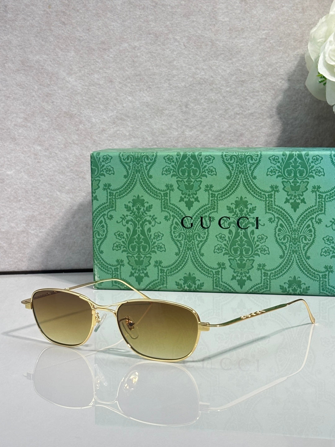 Gucci sunglasses with gold frame and olive tinted lenses, oval shape