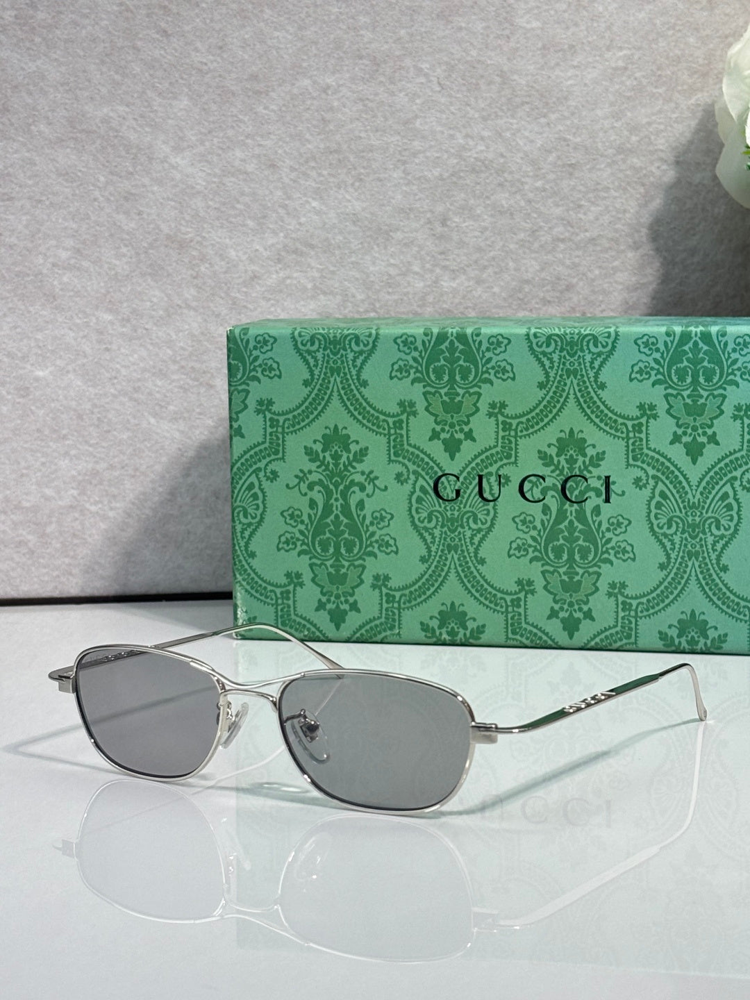 Gucci sunglasses with silver frame and gray tinted lenses, oval shape