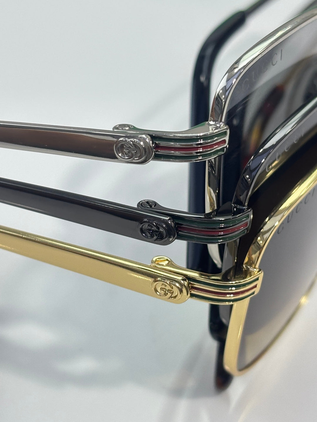 Gucci sunglasses close-up: chrome hinge details with gold arm and black temples