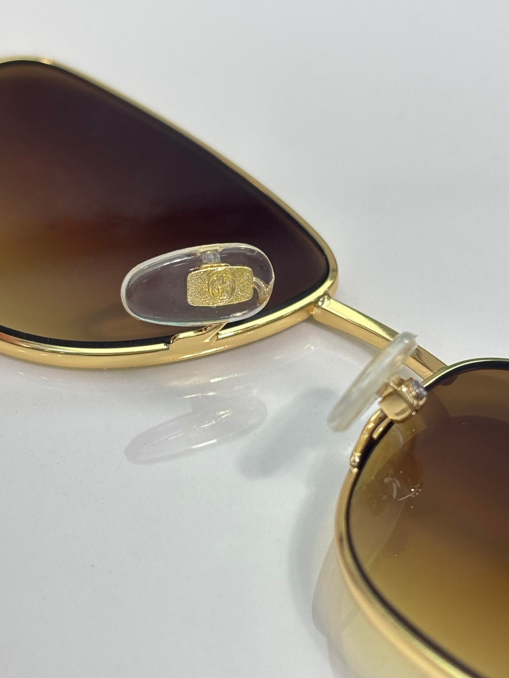 Gucci sunglasses close-up: gold bridge with dark lens and clear rivet