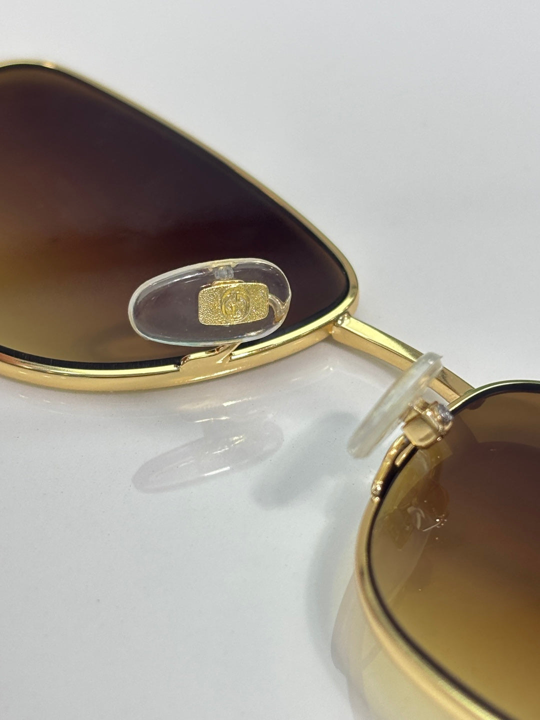 Gucci sunglasses close-up: gold bridge with dark lens and clear rivet