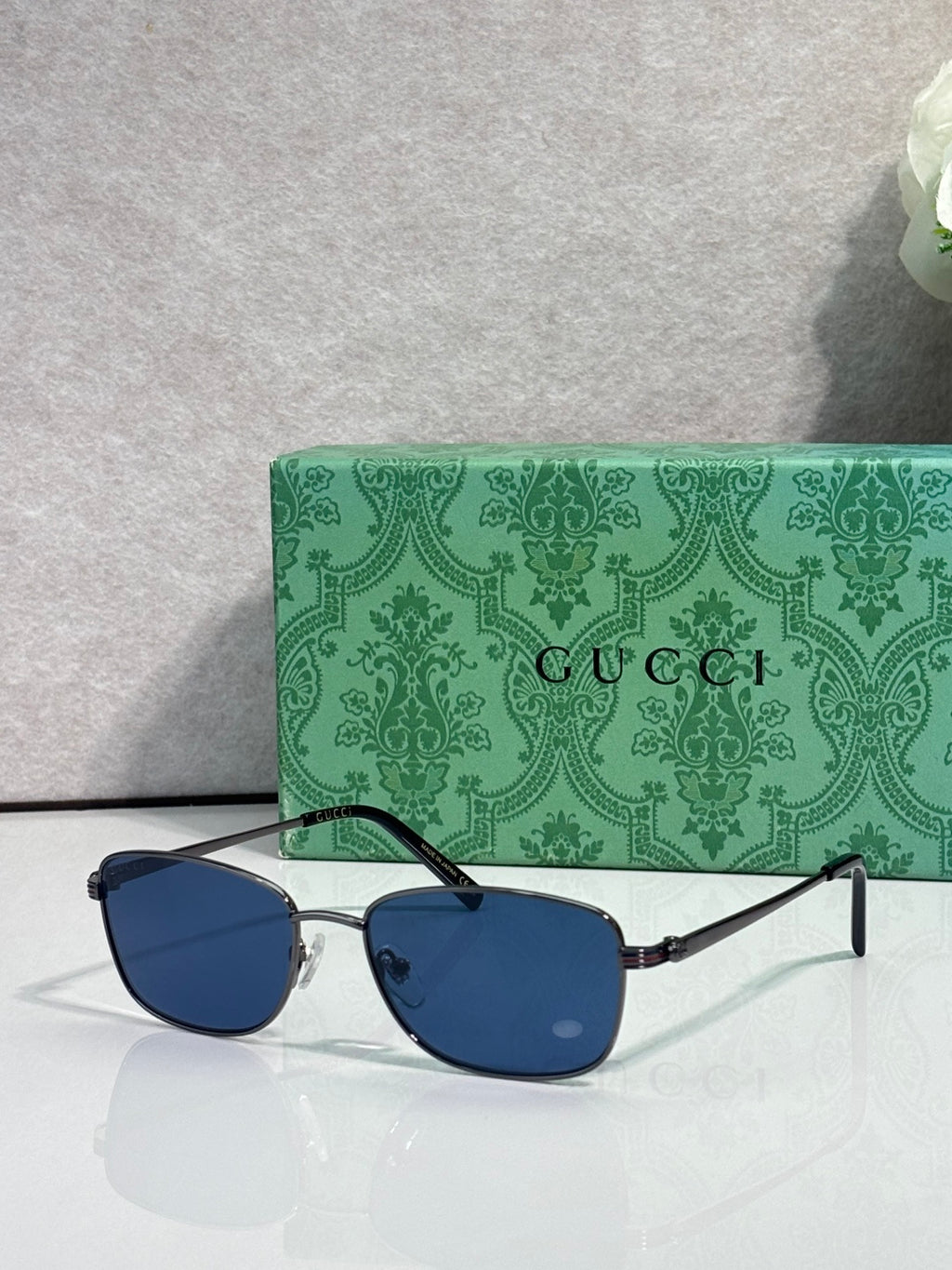 Gucci sunglasses with dark blue lenses and black metal arms, reflective finish
