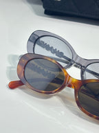 Chanel glasses with overlapping blue and tortoiseshell oval frames and tinted lenses.