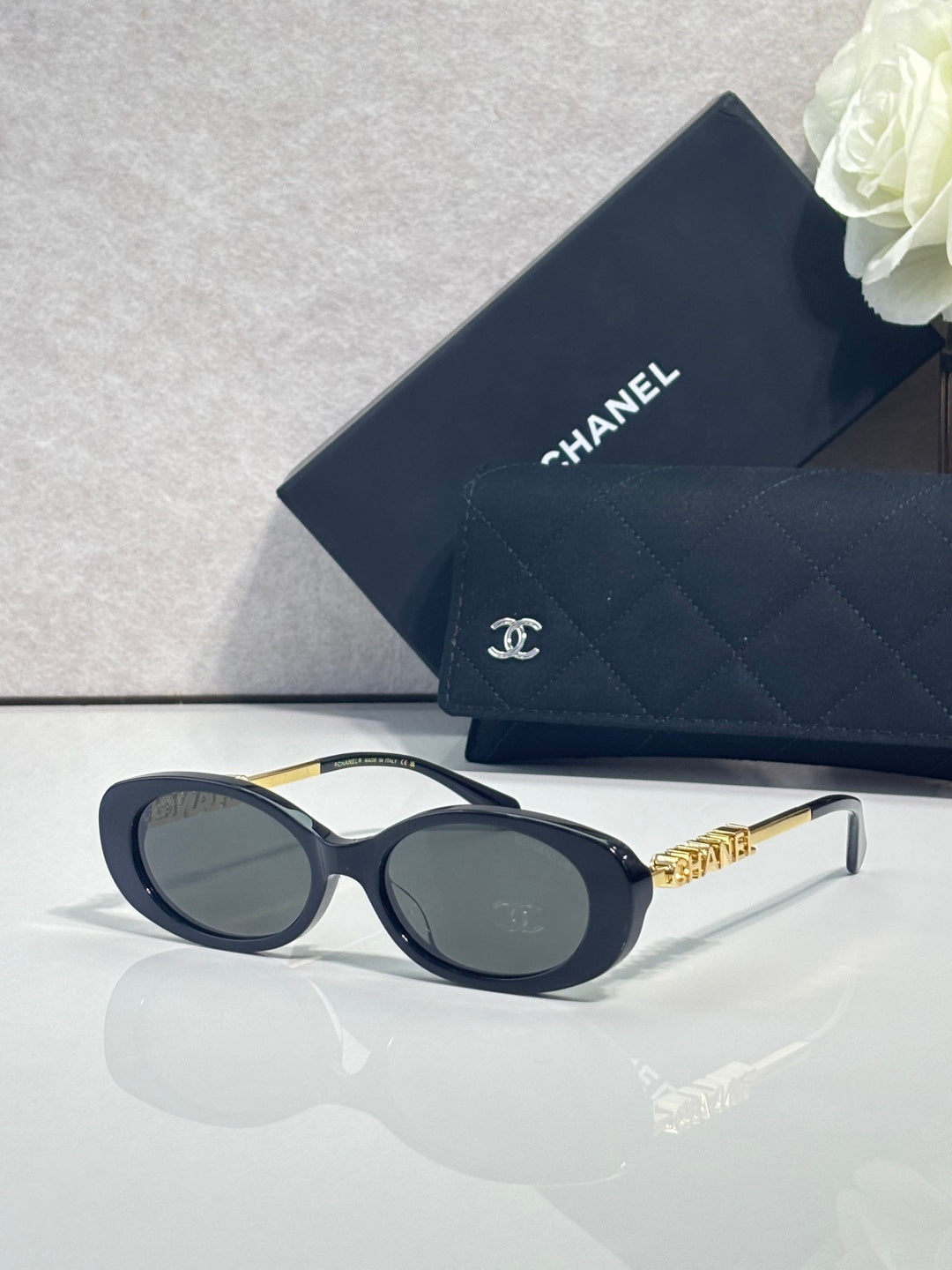 Chanel sunglasses with dark blue oval frames and gold logo detail on temples