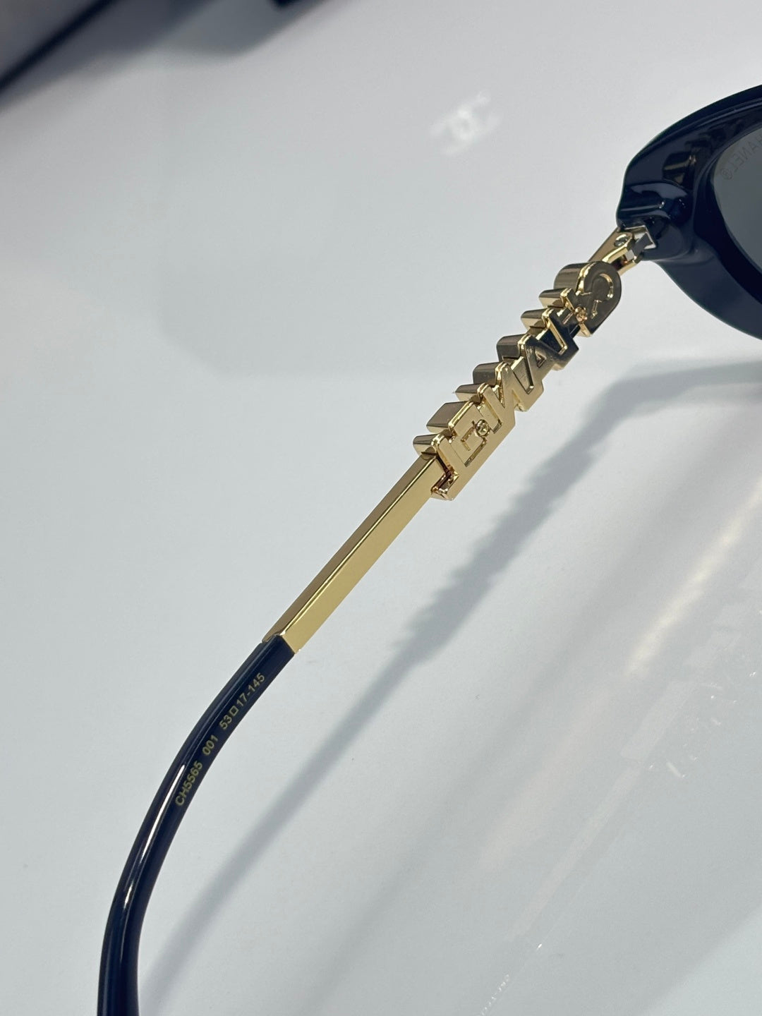Chanel sunglasses close-up of gold temple lettering and dark blue frame end
