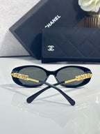 Chanel sunglasses with gold temple branding, resting on navy quilted logo case