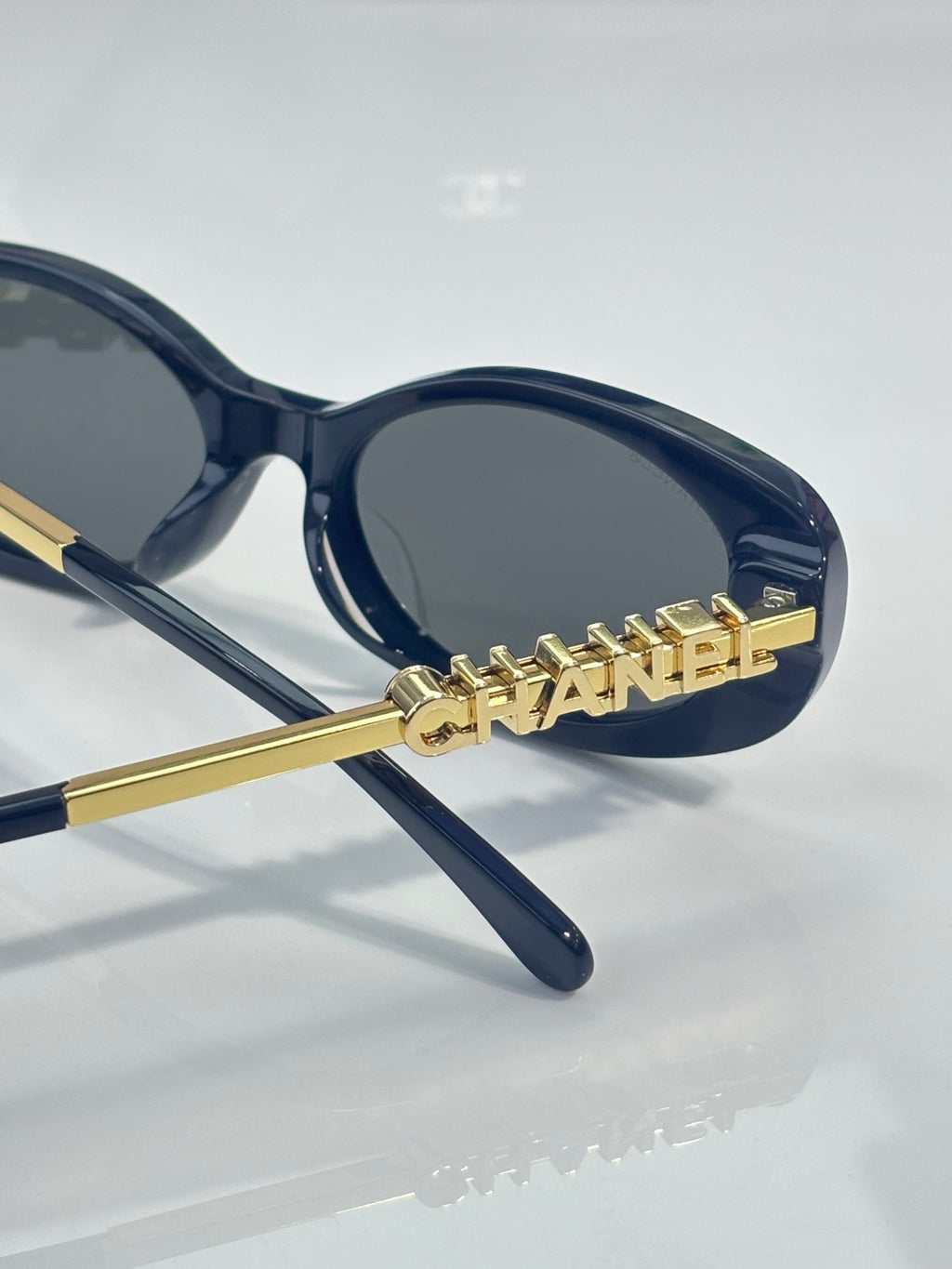 Chanel sunglasses with gold "CHANEL" lettering on dark blue frames and lenses