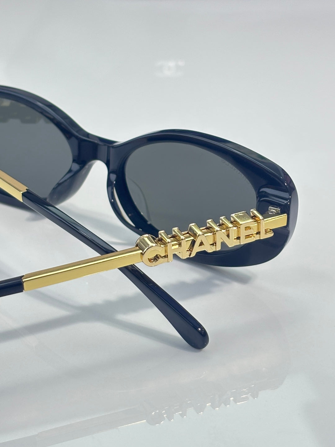 Chanel sunglasses with gold "CHANEL" lettering on dark blue frames and lenses