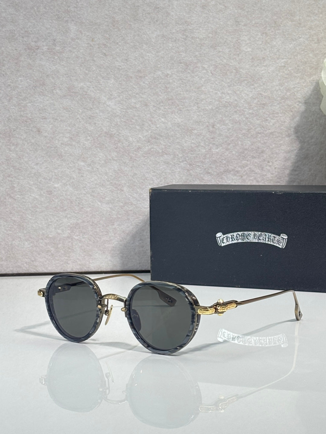 Chrome round glasses with dark lenses and black frames, gold accents