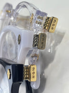 Clear round eyeglasses with gold engraved hinges and blue frame accents