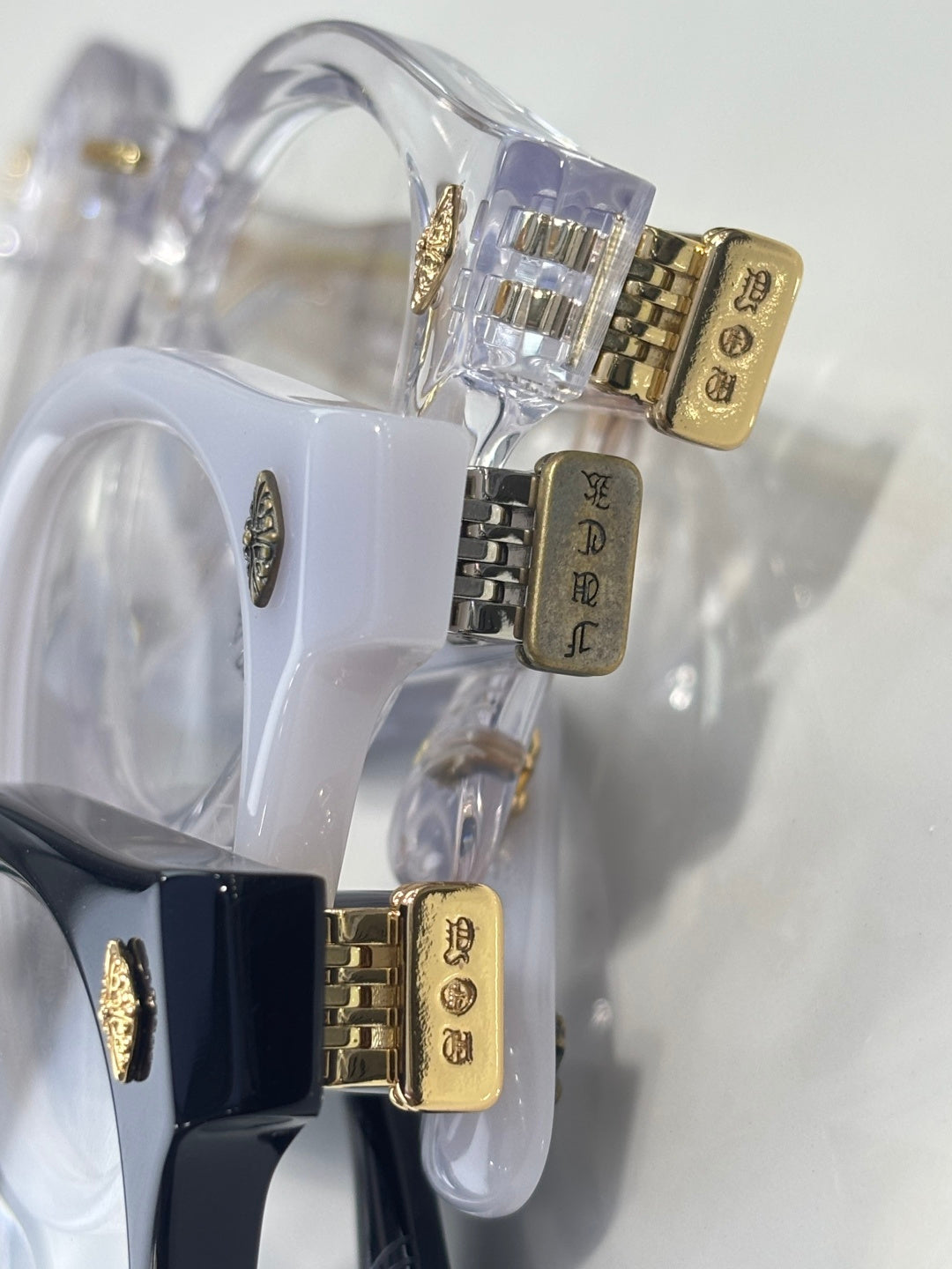 Clear round eyeglasses with gold engraved hinges and blue frame accents