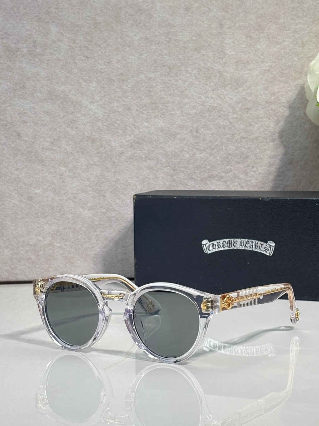 Silver round sunglasses with gray tinted lenses and decorative side detailing