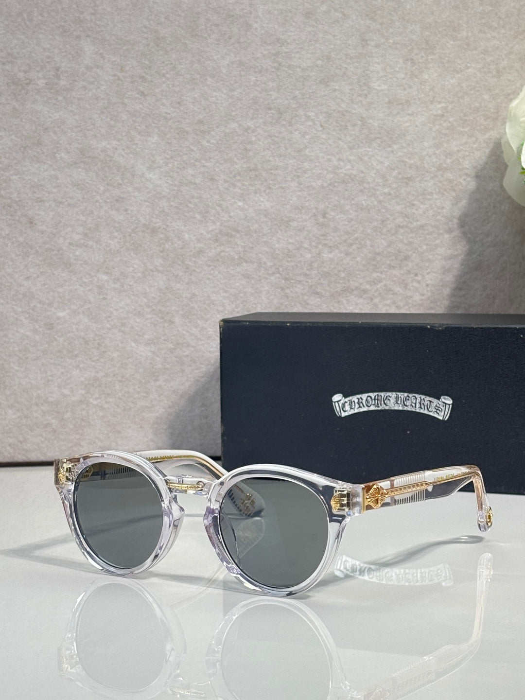 Silver round sunglasses with gray tinted lenses and decorative side detailing