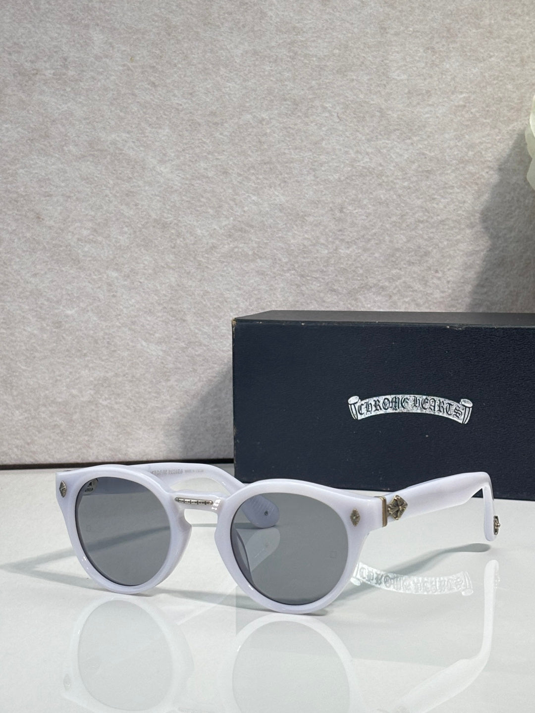 White round sunglasses with gray tinted lenses and gold-tone charm detail