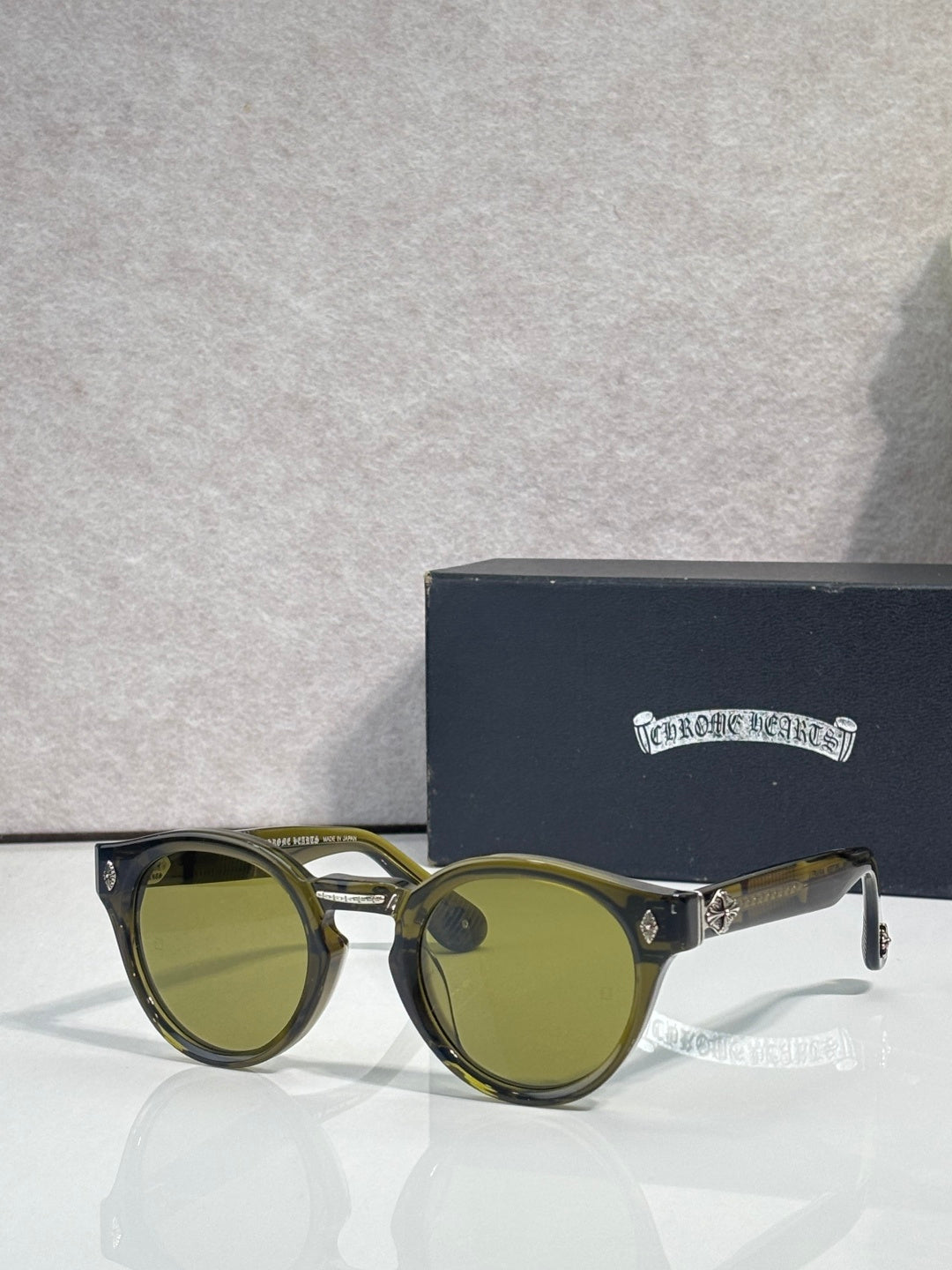 Gold round sunglasses with olive tinted lenses and ornate temple detailing