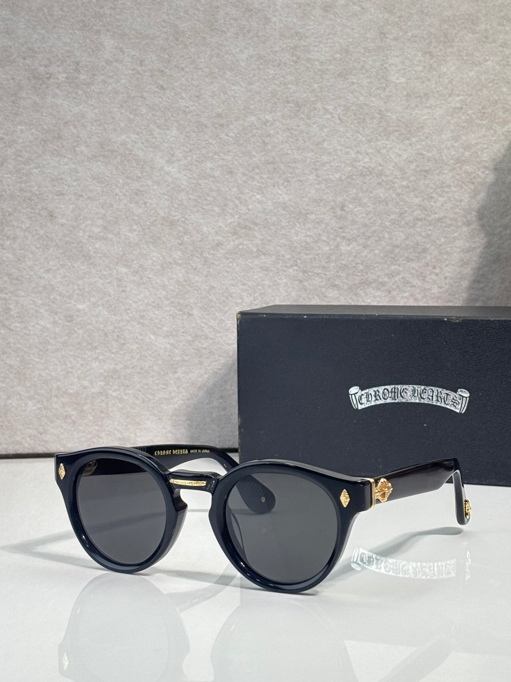 Navy round sunglasses with dark lenses and gold-tone accents on temples