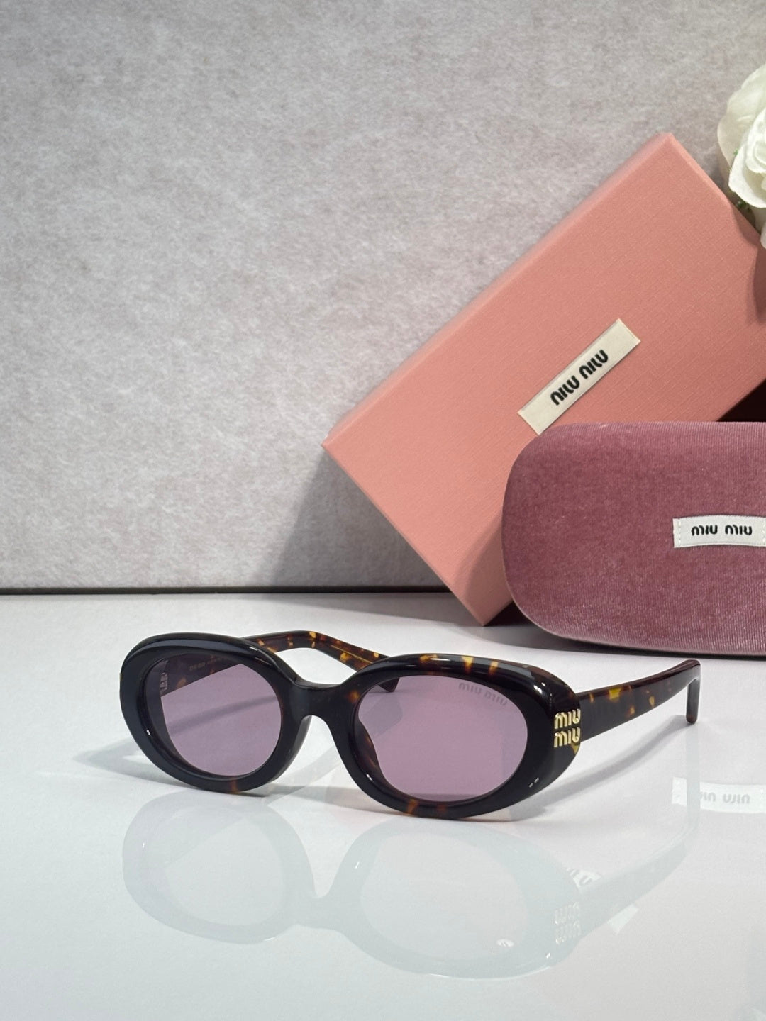 MiuMiu sunglasses with tortoiseshell frame and purple tinted lenses