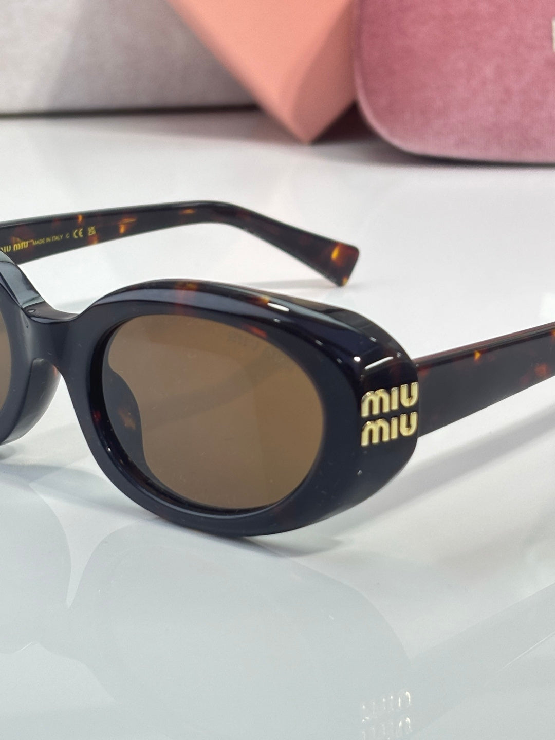 MiuMiu sunglasses close-up: dark frame with brown lenses and tortoiseshell arms