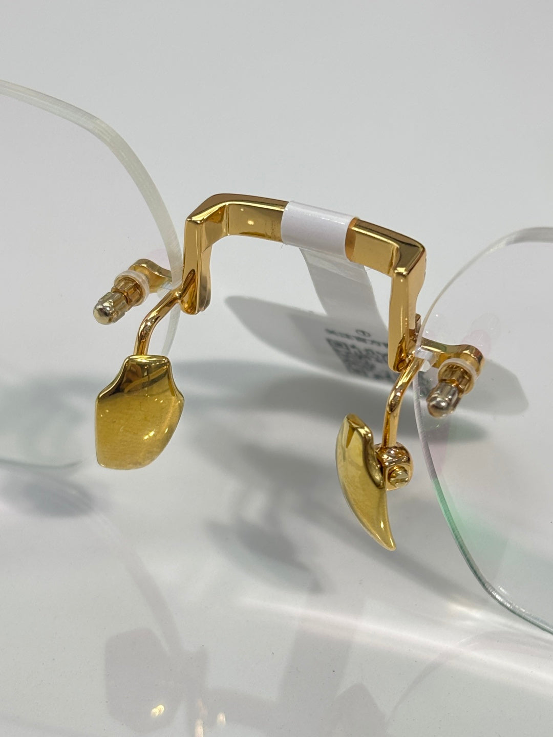 Gold metal eyeglass frame with curved temple and hinge details, clear lens