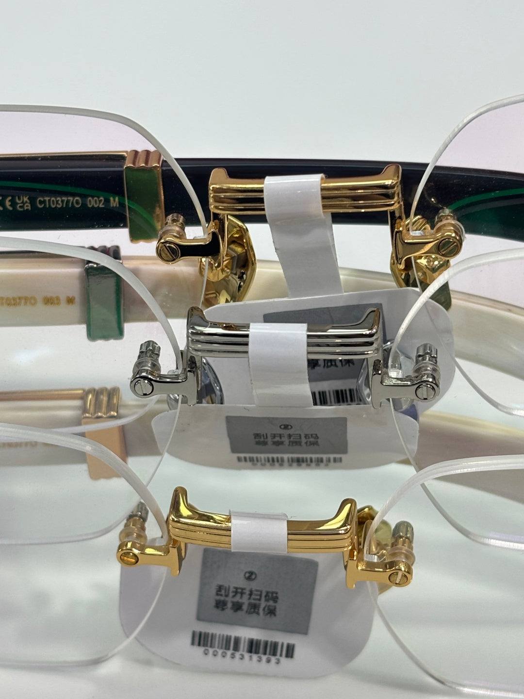 Eyeglasses front hardware with clear lenses; gold-and-silver frame, size tags attached