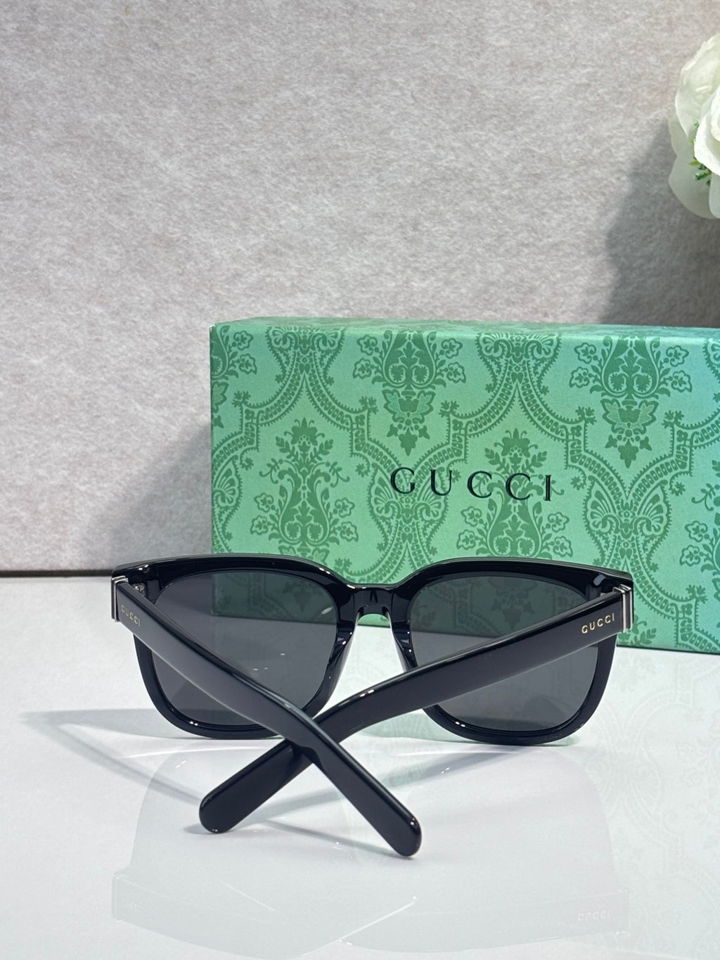 Gucci sunglasses with dark frame and green-tinted lenses, front logo