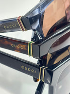 Gucci sunglasses hinge detail with gold-tone accents on dark acetate frame