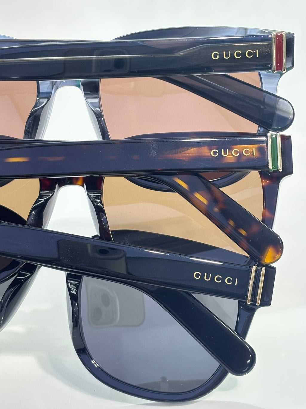 Gucci sunglasses with glossy dark frame and smoky lenses, side logo bar